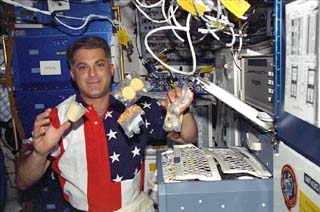  Wolf unpacks various food containers while on the Atlantis's middeck 